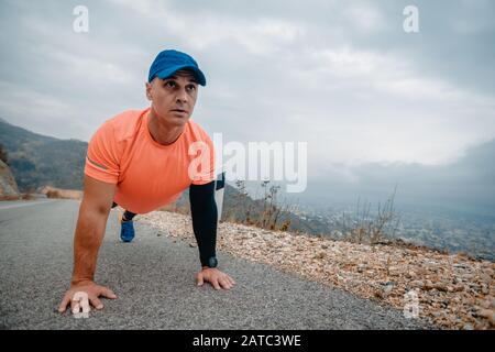 Muscular man wearing sport clothes during preparation for running exercise doing push ups Stock Photo