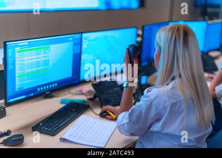 Happy security data center operator colleagues (coworkers) smiling and monitoring the CCTV footage while typing on a keyboard. Stock Photo