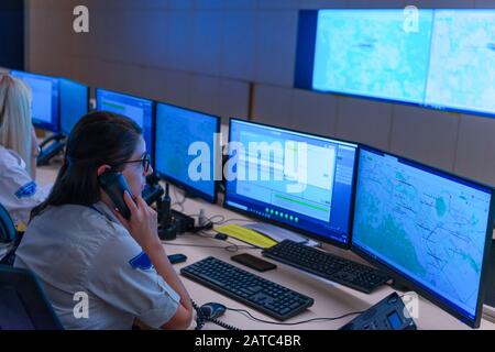 Technical Operator Works at His Workstation with Multiple Displays while talking on the phone, Security guards working on multiple monitors. Stock Photo