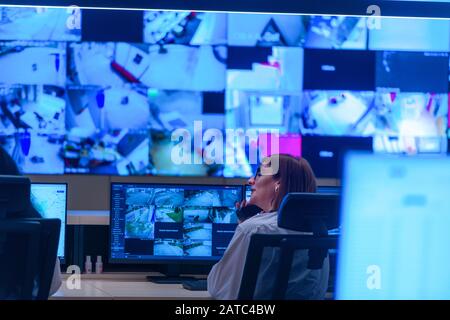 Team working on the System Control Room, Technical Operator Works at His Workstation with Multiple Displays, Security guards working on multiple monit Stock Photo