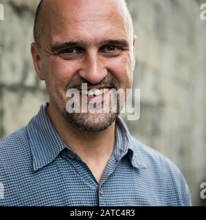Ghent, Flanders / Belgium - 09 02 2019: Casual portrait in close up of a fourty year old smiling white bald man Stock Photo