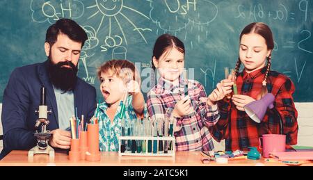 Little kids learning chemistry in school laboratory. school kids scientist studying science. happy children teacher. back to school. students doing science experiments with microscope in lab. Stock Photo