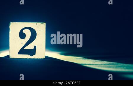 Block with number 2, two, exposed on dark blue background Stock Photo