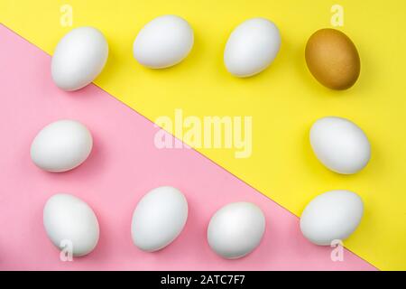 white chicken eggs and one brown egg on a colored background, pink and yellow. egg frame. Background. Natural, raw food. Easter Stock Photo