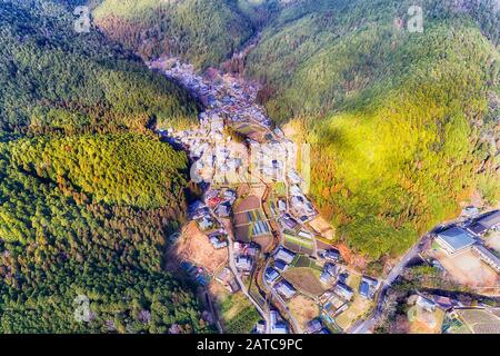 Small agriculture village Ohara in Greater Kyoto area between woods covered mountains with agriculture fields and terraces in aerial top down view. Stock Photo