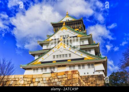 The main keep of traditional historic samurai castle in Osaka with golden ornamental decoration in japanese style against blue sky. Osaka, Japan. Stock Photo