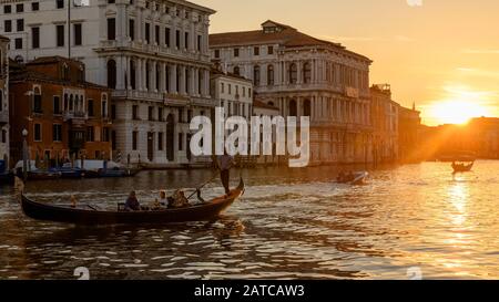 Venice, Italy – May 21, 2017: Gondola with tourists sails on Grand Canal at sunset in Venice. Scenery of town at summer night. Panorama of Venice city Stock Photo