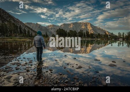 Man looking at mountain reflections in Robinson Lake, Inyo National Forest, California, USA Stock Photo