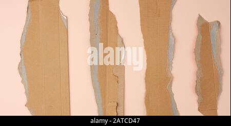 pieces of cardboard corrugated paper torn edges on a beige background, abstract backdrop. Ripped paper texture. Stock Photo