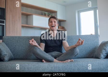 young man sitting in Lotus position on his new sofa Stock Photo