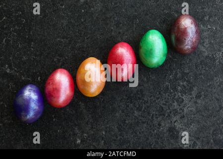 Six colourful eggs in diagonal row on anthracite surface Stock Photo