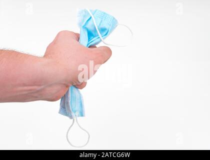 Mans hand hold Blue medical mask isolated on light grey background Stock Photo