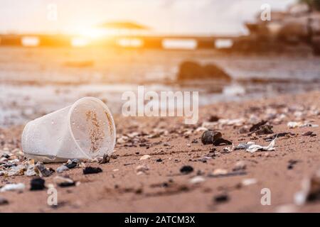 Plastic glasses and garbage on the sandy beach. Environmental & Plastic Awareness. World Environment Day concept. Save earth save life. Stock Photo