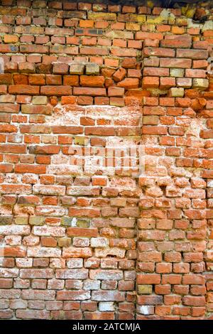 Old ruined orange brick wall with concrete remains and cracks. Damaged antique brick wall texture Stock Photo