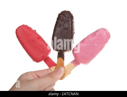 Female hand holding bright candy covered cake popsicles, isolated on white. Chocolate, Strawberry and Raspberry. Fun birthday party treats, easy to ho Stock Photo