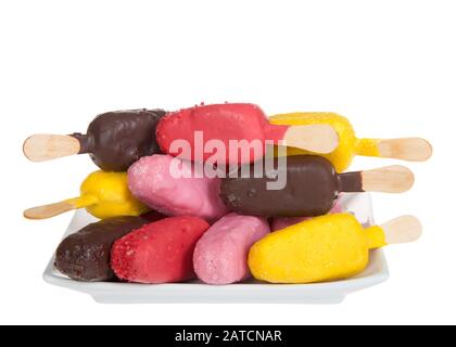 Colorful candy covered cake popsicles on a white plate alternating flavors and direction of cake pops, isolated on white. Fun birthday party treats, e Stock Photo