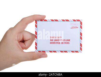 Young caucasian hand holding tiny letter addressed to Santa, isolated on white background. Stock Photo