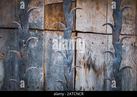 Detail of an antique wooden door with cast iron decorative bars Stock Photo