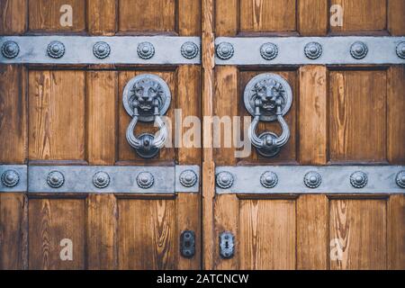 Detail of an antique wooden door with lion knockers made of cast iron Stock Photo