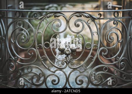 Antique decorative cast iron fence in neoclassical style surrounding a small romantic fountain Stock Photo