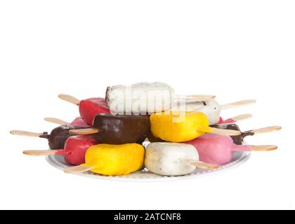 Assortment of colorful cake pop popsicles in various flavors and colors on an off white porcelain plate stacked, isolated on white. Stock Photo