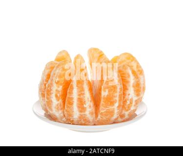 Whole sumo orange peeled and separated sitting on small round plate isolated. Native to Japan, Sumo oranges are a hybrid citrus fruit that's a cross b Stock Photo
