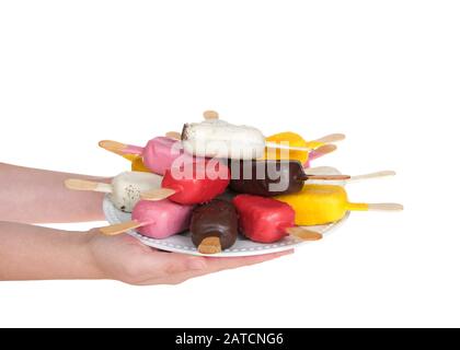 Caucasian female hand holding plate of colorful candy covered cake popsicles on a white plate, five colors and flavors, isolated on white background. Stock Photo