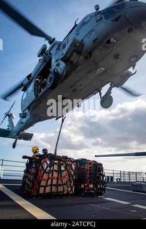 PACIFIC OCEAN (Jan. 28, 2020) Boatswain’s Mate 2nd Class Nicole Moore, from Edmonton, Okla., left, and Boatswain’s Mate 3rd Class Richard Martinez, from Colorado City, Texas, attach cargo legs to an MH-60S Sea Hawk, assigned to the “Eightballers” of Helicopter Sea Combat Squadron (HSC) 8, during a vertical replenishment-at-sea with the Ticonderoga-class guided-missile cruiser USS Bunker Hill (CG 52) Jan. 28, 2020. Bunker Hill, part of the Theodore Roosevelt Carrier Strike Group, is on a scheduled deployment to the Indo-Pacific. (U.S. Navy photo by Mass Communication Specialist 3rd Class Nichol Stock Photo