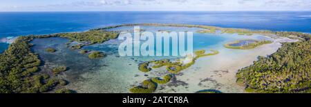 A remote tropical island in the Molucca Sea is fringed by mangrove forest surrounding a shallow lagoon. This island sits amid the Coral Triangle. Stock Photo