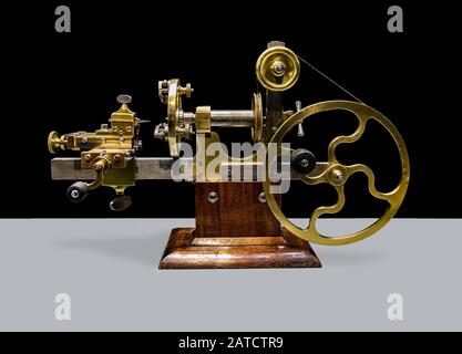 A ancient precision Lathe from 19th century, on black and white background. A historic machinery for processing clock mechanisms. Stock Photo