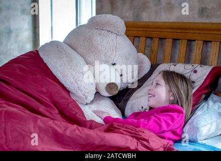 Big bear and little girl have bedtime pillow talk Stock Photo