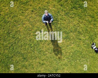 Man looking up while flying a drone with a green grass background. Victoria, Australia. Stock Photo