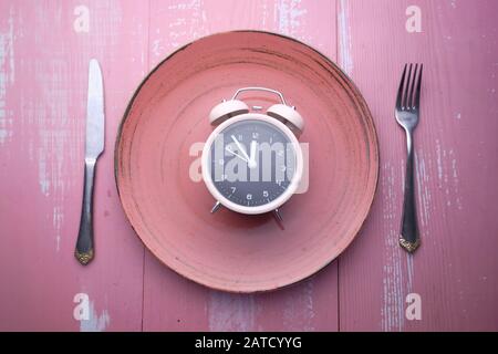 alarm clock on plate on pink background Stock Photo