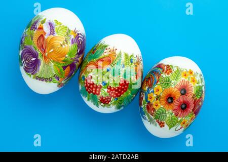Decorated Paschal chicken eggs on blue background. Easter colored gift card