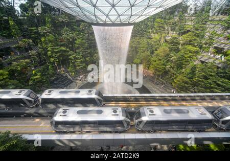 Singapore - August 3, 2019 - Skytrains traveling past Singapore's Jewel Changi Airport complex and Rain Vortex waterfall Stock Photo