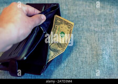 black wallet with dollars in the hands on grey background. financial wellness. copy space. toned. Stock Photo