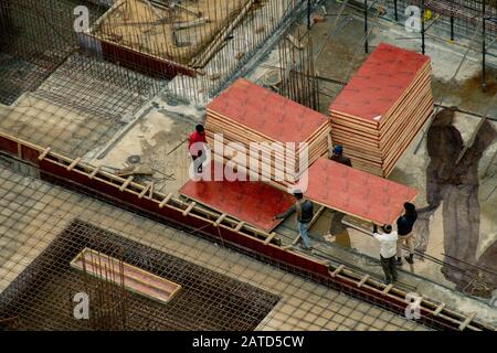 Construction workers in India moving wooden boards on near a work site Stock Photo