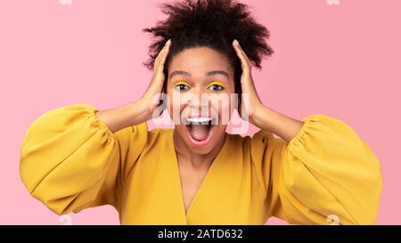 Happy afro woman screaming and grabbing her head Stock Photo