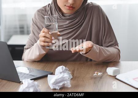 Depressed Muslim Woman Taking Drugs At Workplace In Office Stock Photo