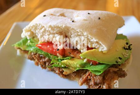 Sliced beef with fresh vegetable sandwich cut in half on a white plate Stock Photo