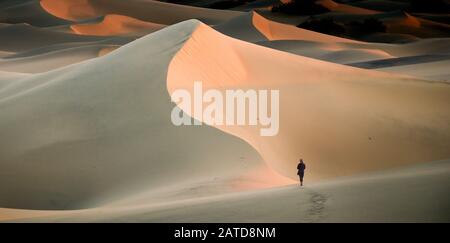 Woman walking in sand dunes, Mesquite Flat Sand Dunes, Death Valley, California, USA Stock Photo