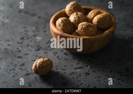 inshell walnuts in olive wood bowl on terrazzo countertop, shallow focus Stock Photo