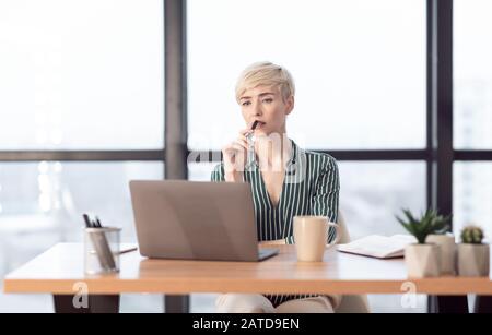 Thoughtful Business Lady At Laptop Thinking Working At Workplace Stock Photo