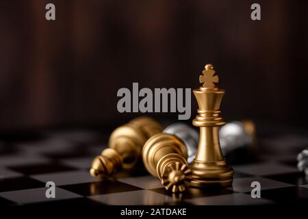 gold king standing in the midst of falling chess on board in game Stock Photo