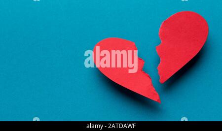 Broken red paper heart on a blue background Stock Photo