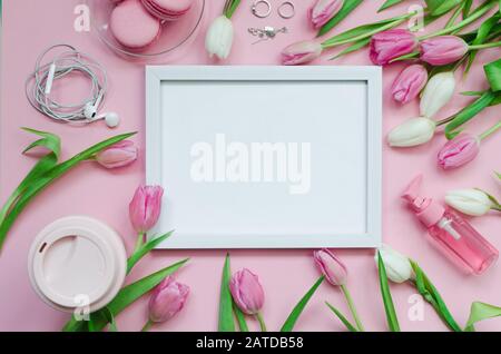 White picture, coffee cup, spring tulip flowers and pink macarons on pastel table top view. Greeting for Womans or Mothers Day. Flat lay. Stock Photo