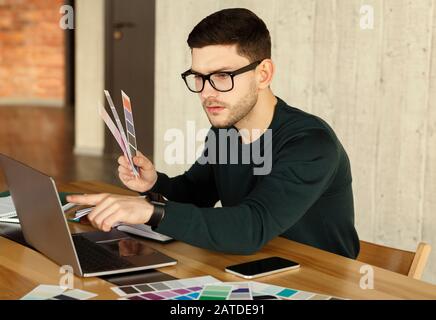 Designer Freelancer Working On Laptop Choosing Color Samples In Office Stock Photo