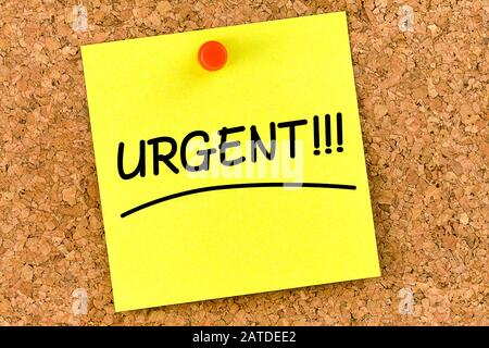closeup post it note on corkboard with urgent message on it Stock Photo