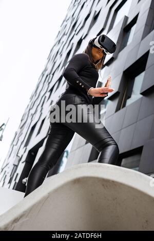 Side View of Excited Woman With VR Technology In Futuristic City Stock Photo