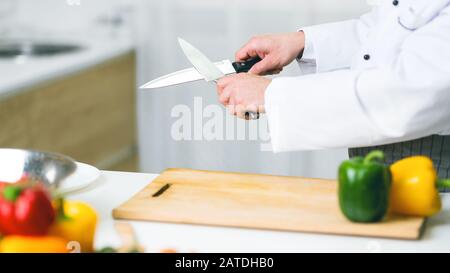 Unrecognizable Cook Guy Sharpening Knives In Restaurant Kitchen, Panorama, Cropped Stock Photo